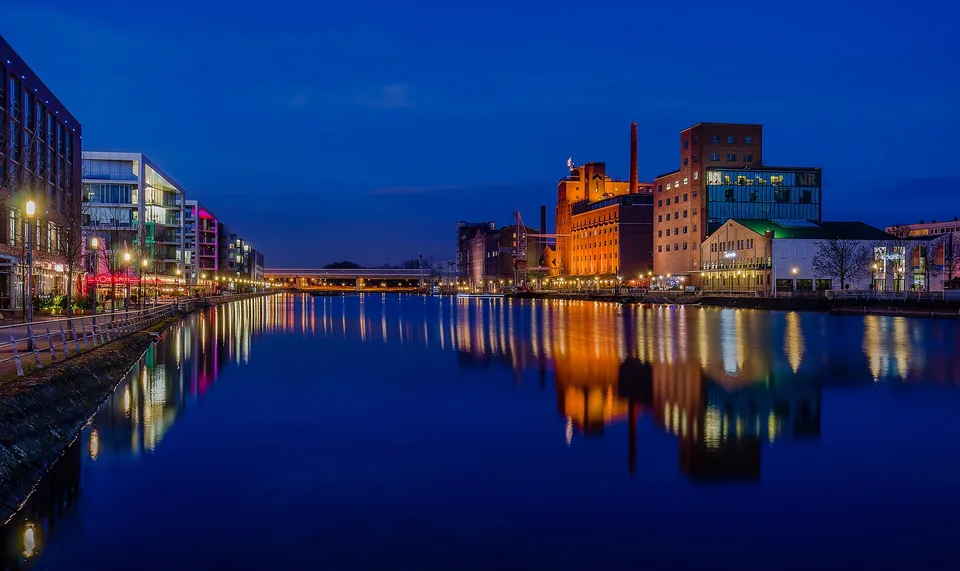 Duisburger Innenhafen mit beleuchteten Gebäuden und Spiegelungen zur blauen Stunde