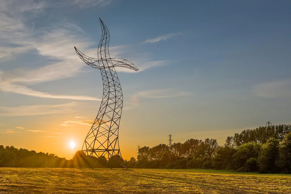 Skulptur eines geschwungenen Strommasts in Oberhausen im Sonnenuntergang